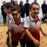 Three young boys in Gumbaynggirr Giingana Freedom School uniforms with white ochre on their faces learn about Aboriginal culture through the Living Classrooms pilot program