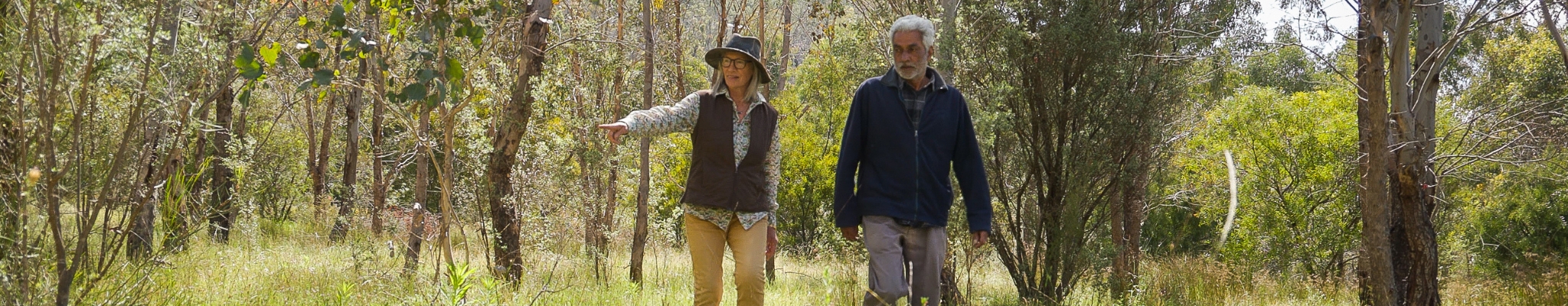 Two people walk through a property conserved for its native vegetation and Australian biodiversity.